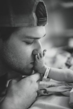 a black and white photo of a man holding a baby's hand to his mouth