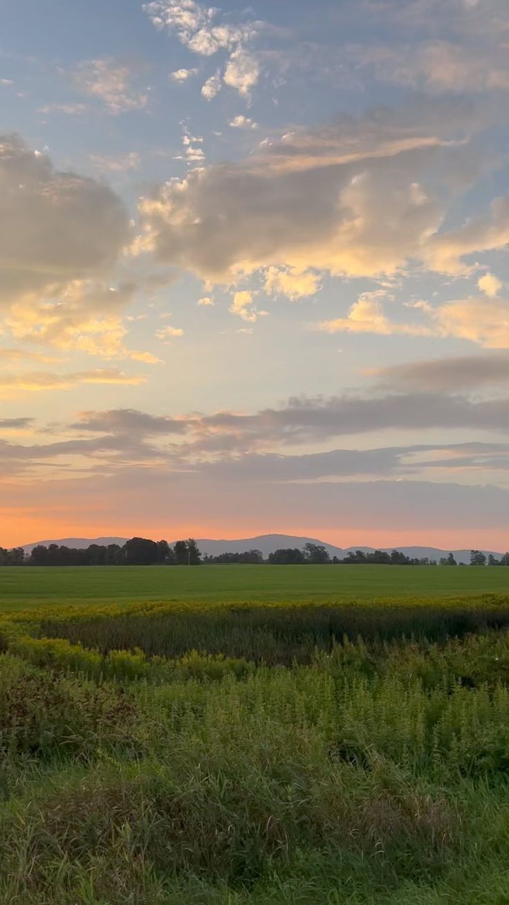 the sun is setting over an open field