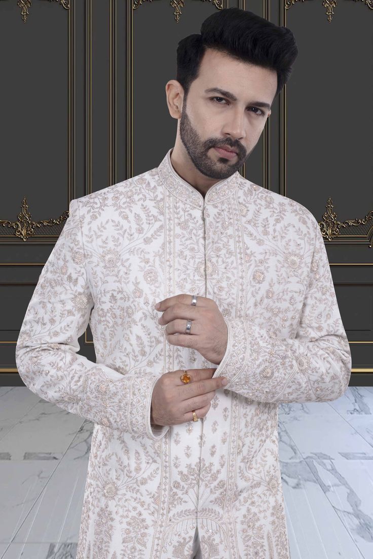 This impeccable sherwani, adorned with luxurious stones and intricate embroidery, exudes sophistication and elegance. Perfect for the stylish groom, it is a timeless masterpiece that will make a lasting impression. Indulge in the opulence and elevate your wedding day look with this R14-S71 sherwani. Elegant Cream Bandhgala With Chikankari Embroidery, Unstitched Off White Bandhgala With Long Sleeves, Elegant Bandhgala With Chikankari Embroidery For Designer Wear, Elegant Designer Embroidered Sherwani, Off White Unstitched Bandhgala With Long Sleeves, Elegant Embroidered Designer Sherwani, Elegant Off White Bandhgala With Zari Work, Elegant Embroidered Sherwani For Designer Wear, White Elegant Nehru Jacket For Designer Wear