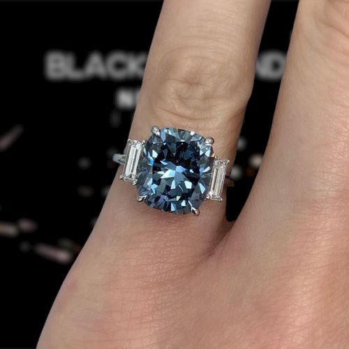 a woman's engagement ring with a blue diamond