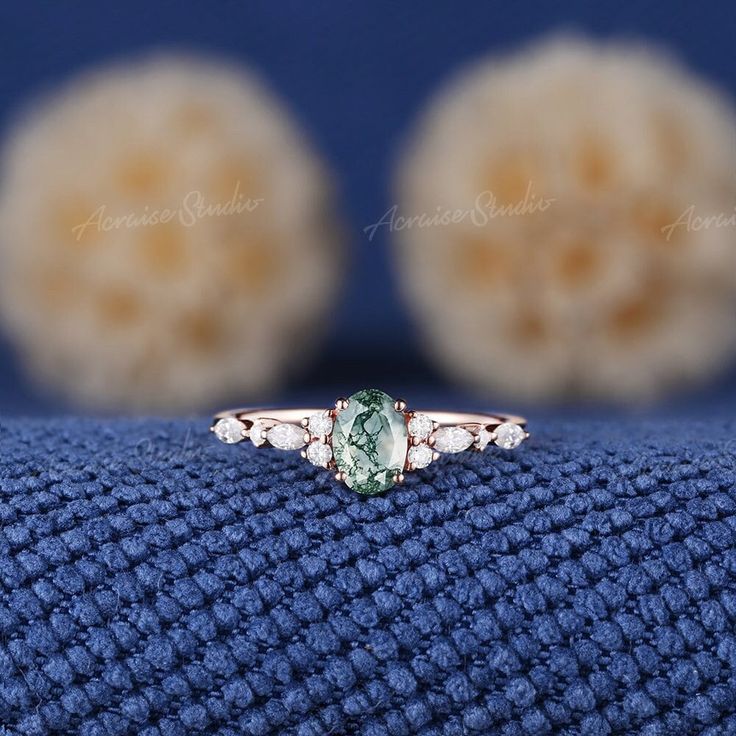 an oval cut green and white diamond ring on top of a blue cloth with three balls in the background