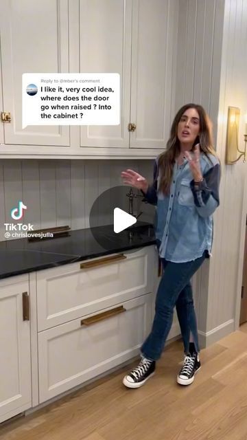 a woman standing in front of a kitchen counter with an ad on the wall behind her