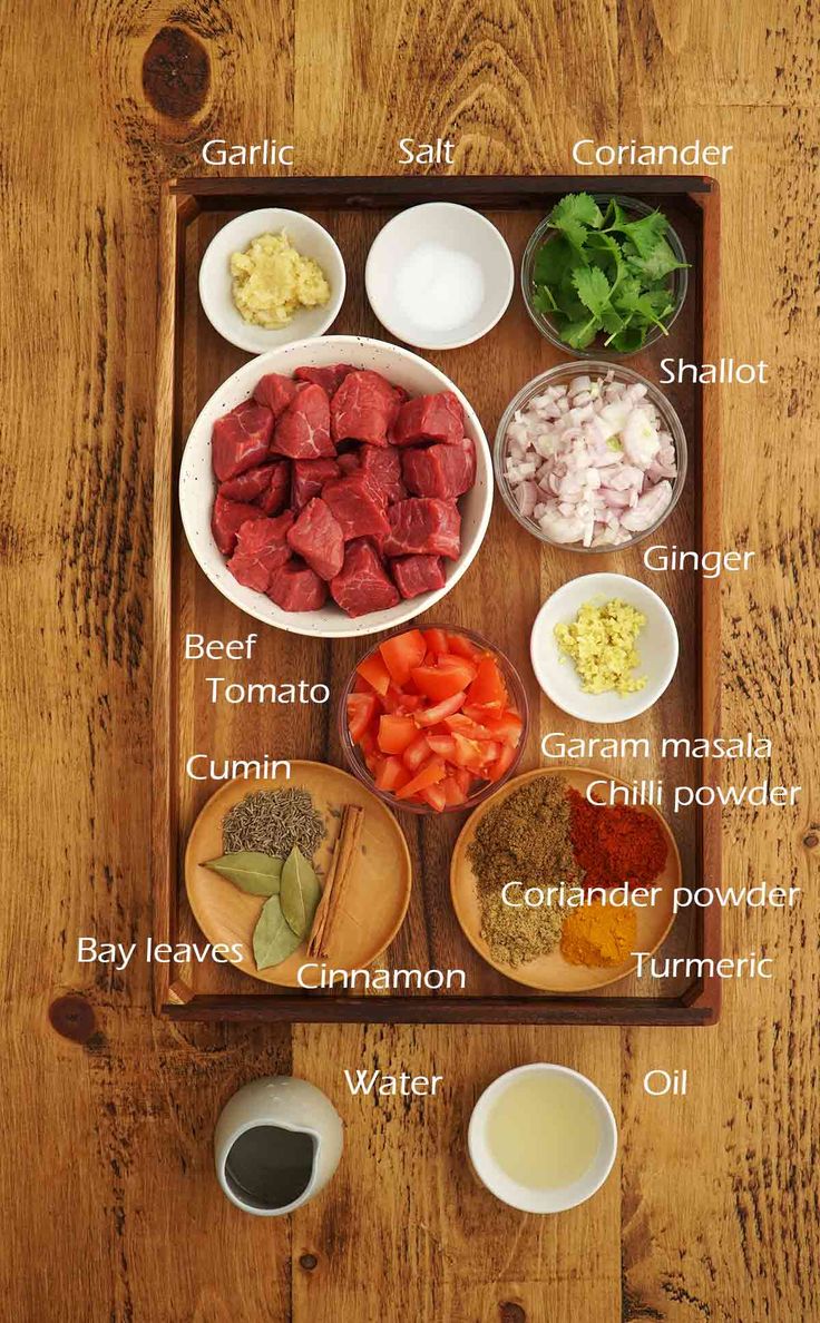 the ingredients for this meat and vegetable dish are shown on a wooden tray, including tomatoes, onions, carrots, celery, onion, garlic, green beans, salt and water