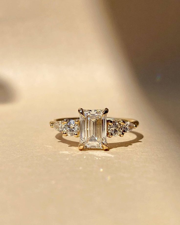 2 CT Emerald Cut Moissanite Solitaire Ring | Hidden Halo Engagement Ring | Dainty Wedding Ring | Unique Proposal Ring | Bridal Gifts/Ring ❤ ITEM DETAILS:- ✦ Brand: The American Gold House (TAGH) ✦ Handmade, high-quality item! ✦ Material: Solid 10K/14K/18K Gold, 950 Platinum and 925 Sterling Silver ✦ Diamond Type: Moissanite Diamond ✦ Diamond Cut: 6x8 MM Emerald ✦ Diamond Weight: 2.0 CT ✦ Main Stone Color: Colorless ✦ Width of Band: 1.8 MM (Bottom) ✦ Diamond Clarity: VVS/VS ❤ ACCENT/HALO DIAMONDS:- ✦ Side Stone Material: Moissanite Diamond ✦ Side Stone Shape: Round Cut ✦ Side Stone Carat Weight: 0.50 CT ✦ Side Stone Color: Colorless ✦ Diamond Clarity: VVS/VS ------------------------------------------------------------------------------ 💎 Moissanite VS Diamond 💎 --------------------------- Colored Moissanite, Solitaire Bands, Crunchy Granola, Ring Inspo, Cute Engagement Rings, Wedding Ring For Her, Future Engagement Rings, Emerald Cut Engagement, Emerald Cut Moissanite