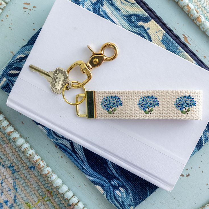 a keychain with blue flowers on it sitting next to an envelope