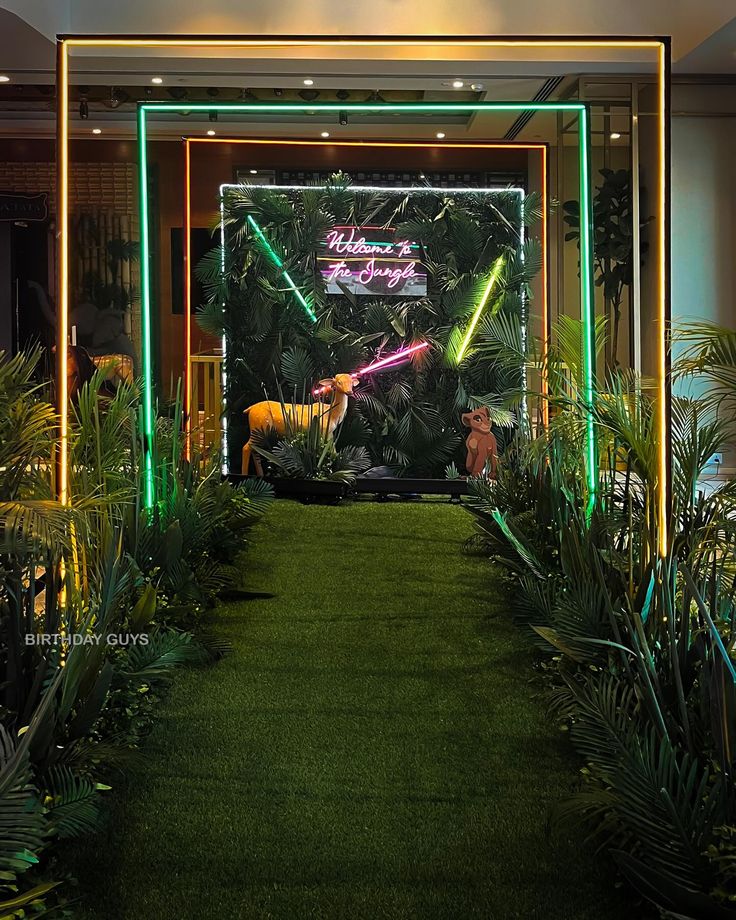 an entrance to a building with plants and neon lights on the walls, along with artificial grass