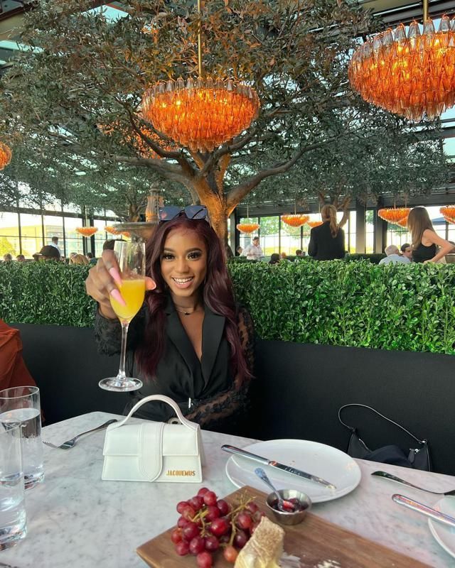 a woman sitting at a table holding up a wine glass