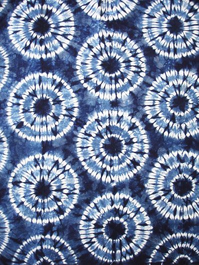 blue and white tie - dyed fabric with circular designs on it's surface,