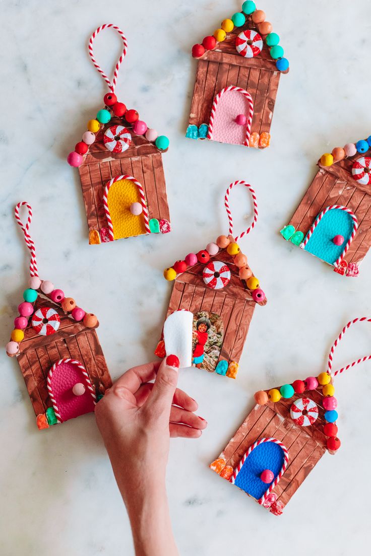 someone is decorating their gingerbread house ornament with candy and marshmallows