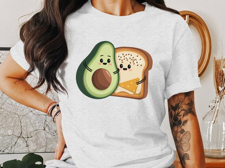 This cute avocado toast T-shirt features an adorable graphic of avocado and toast with happy expressions. Perfect for foodies and anyone who loves a fun, casual look. Enjoy the charming design and spread joy with your unique style. Great for everyday wear. Product Features: Fabrication: 100% Airlume combed and ring-spun cotton, 32 single 4.2 oz. (Ash - 99% Airlume combed and ring-spun cotton, 1% poly) Seams: Side-seamed Fit: Retail Fit Sizing: Unisex Sizing Label: Tear away label assisted with a Avocado And Toast, Cartoon Food, Cute Avocado, Casual Tee, T Shirt Funny, Boys T Shirts, Avocado Toast, Food Print, Boy's Clothing