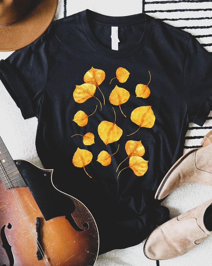 T-shirt featuring a botanical illustration of golden yellow Aspen tree leaves in the fall. Fall in love with our perfect autumn graphic tee you won't find anywhere else. Printed on a Black shirt, made from durable lightweight cotton.  Unisex fit - boxy and long. T-SHIRT SIZING: *All measurements in inches XSLength 27 / Width 16 ½ SLength 28 / Width 18 MLength 29 / Width 20 LLength 30 / Width 22 XLLength 31 / Width 24 2XLLength 32 / Width 26 3XLLength 33 / Width 28 How it's made: * All prints are Casual Yellow T-shirt For Fall, Yellow Graphic Tee For Fall, Yellow T-shirt With Screen Print For Fall, Yellow Cotton T-shirt For Fall, Mustard Short Sleeve Tops For Fall, Fall Cotton T-shirt With Plants Print, Fall Crew Neck T-shirt With Plants Print, Fall Plants Print Cotton T-shirt, Yellow T-shirt With Plants Print