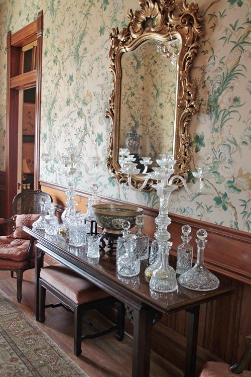 a dining room table with glassware on it and a mirror hanging above the table