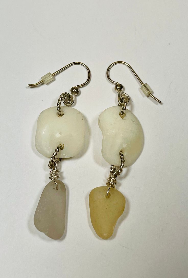 "Sea glass lucky stone dangle earrings. One is lavender and the other one is a beige. The lucky stones are an ivory like stone (inner ear bone of a sheep head fish). They measure 2 1/2\" length, I used twisted silver plated jump rings for the connectors. The ear wire is also silver plated with plastic backings.  Awesome gift idea for the upcycling, ecofriendly, beach lover in your life.  Perfect for a beach wedding! Check out my other items at www.etsy.com/shop/pierbeachglass My sun catchers hav Cream Earrings With Ear Wire For Gifts, Unique White Beach Earrings, Nickel Free Cream Dangle Earrings, Cream Dangle Earrings Nickel Free, Handmade Sea Glass Dangle Earrings, Adjustable Nickel Free Sea Glass Earrings, Nickel-free Adjustable Sea Glass Earrings, Adjustable Nickel-free Sea Glass Earrings, White Wire Wrapped Jewelry For Beach