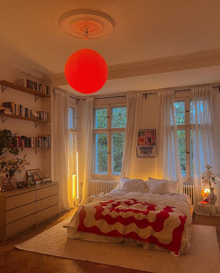 a bed room with a neatly made bed and a red ball hanging from the ceiling