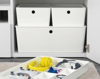 an open drawer on the floor in front of a white cabinet with two bins