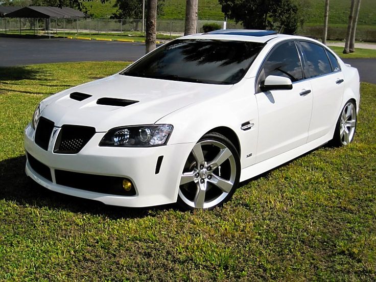 a white car parked on top of a lush green field