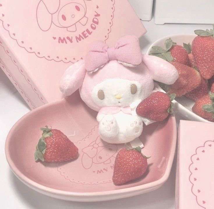 a pink hello kitty plate with strawberries and a small stuffed animal in the bowl