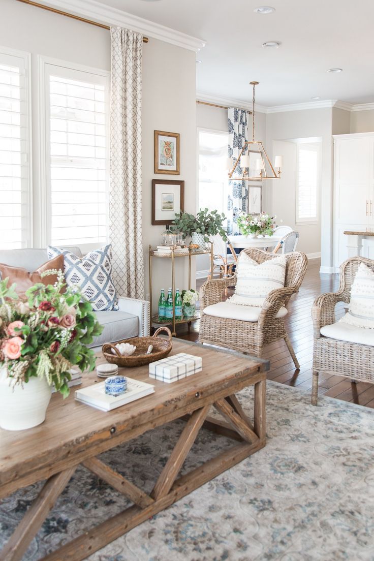 a living room with wicker furniture and flowers on the coffee table in front of it