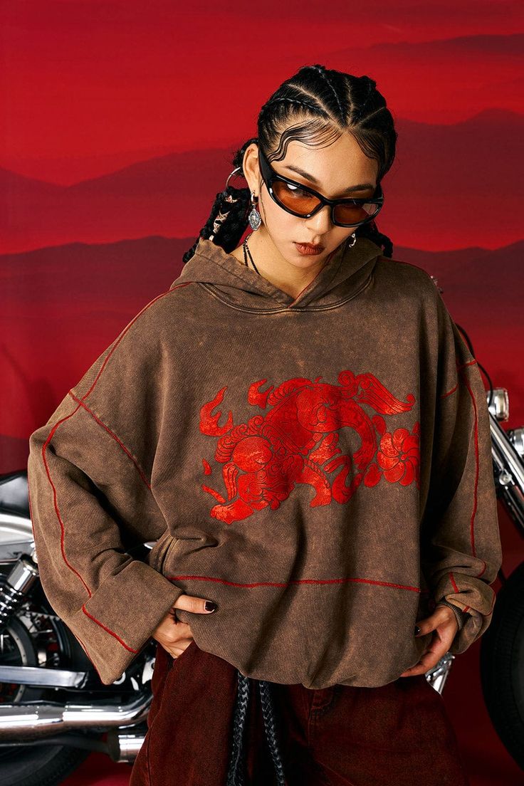 The Lion Heavyweight Oversized Hoodie seamlessly blends traditional elements with bold modern aesthetics, making it a unique addition to your casual wear collection. The hoodie showcases striking lion totem graphics sprawling across the front, accompanied by vibrant red stitches at the seams that instantly catch the eye. The garment underwent a washing process that enhanced its earth-tone color, yielding a rich, layered visual effect. Traditional Chinese knot button closures on the side pockets Earth Tone Hoodie, Creative Hoodies, Lion Totem, Hoodie Design Ideas, Graphic Hoodies Aesthetic, Knot Button, Creative Shoot, Clothes Board, Shoot Poses