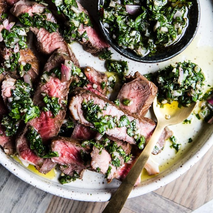 a plate with steak, broccoli and other food on it next to a spoon