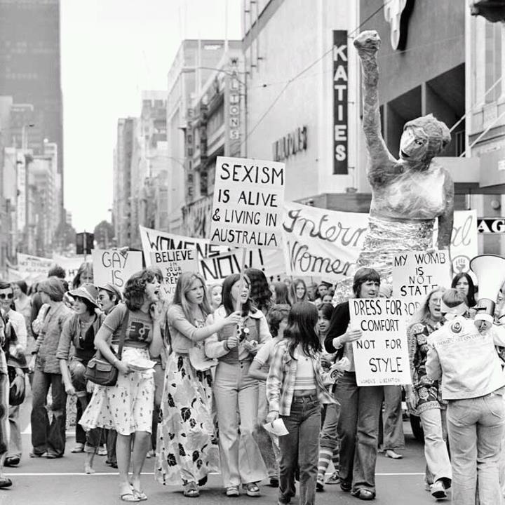 black and white photograph of people marching down the street with signs in front of them