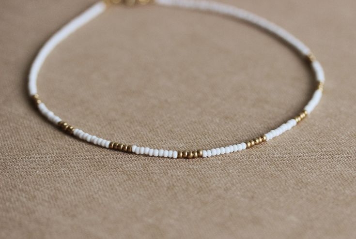 This dainty simple necklace was made of white and gold tone matt czech glass seed beads,two layers of strong nylon thread, gold plated clasp with gold tone lobster clasp. Perfect minimalistic summer jewelry! You can wearing it with other chokers or alone! It's not afraid of water and your sun protection cream. The length of necklace is about 41.5 cm or about 16.3 inches and 3 cm of adjustable length gold tone chain. (Please,let me know if you need other length) Other necklaces you can find in my Minimalist White Beaded Necklaces For Everyday, Minimalist White Beaded Necklace For Everyday, Adjustable White Choker For Everyday Wear, Minimalist Everyday White Beaded Necklaces, White Gold Beaded Necklace For Beach, Delicate White Beaded Necklaces With Tiny Beads, Minimalist White Beaded Necklace With Tiny Beads, Dainty White Beaded Necklaces For Everyday, Everyday Dainty White Beaded Necklaces