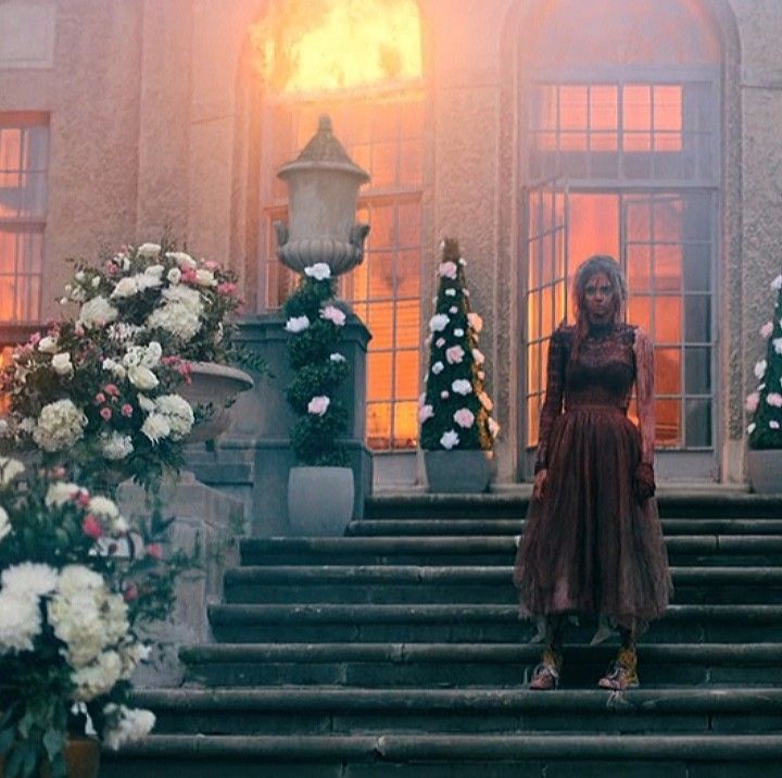 a woman standing on the steps in front of a building with flowers growing out of it