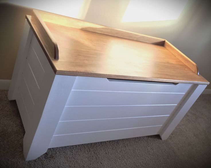 a white dresser with wooden top in a room next to a wall and carpeted floor