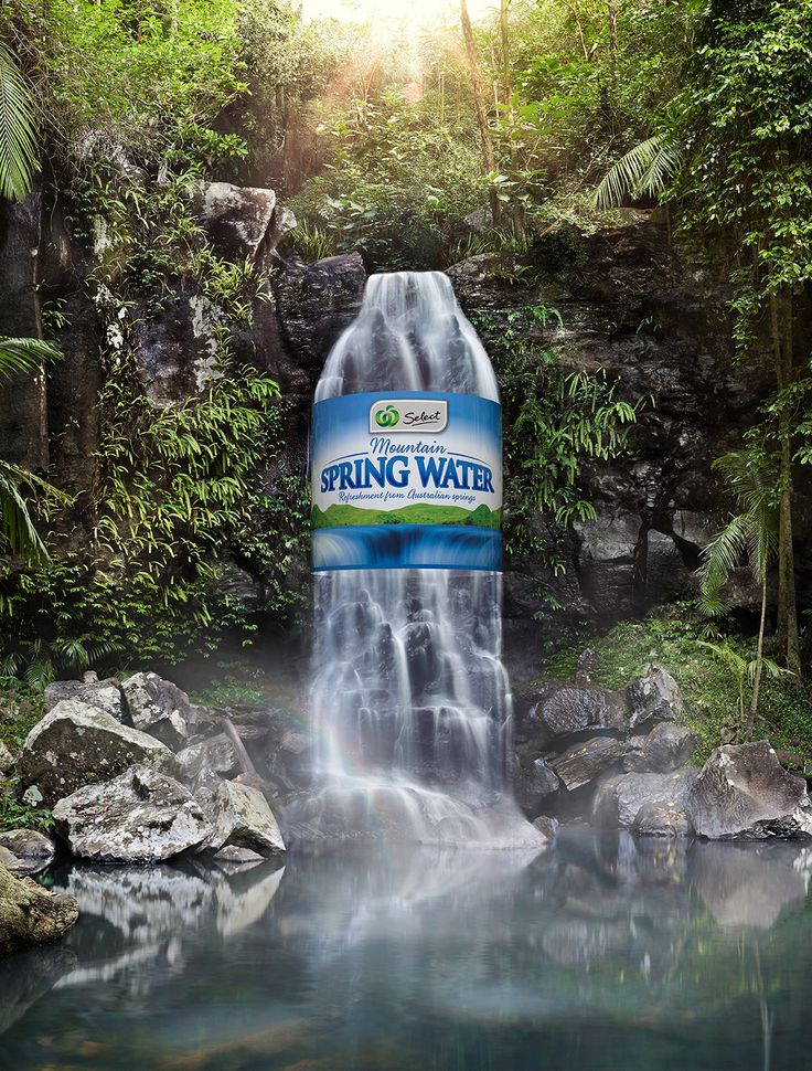 a bottle of spring water in front of a waterfall