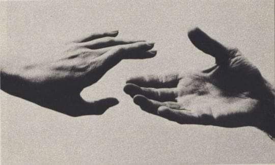 two hands reaching out towards each other in black and white, against a light gray background