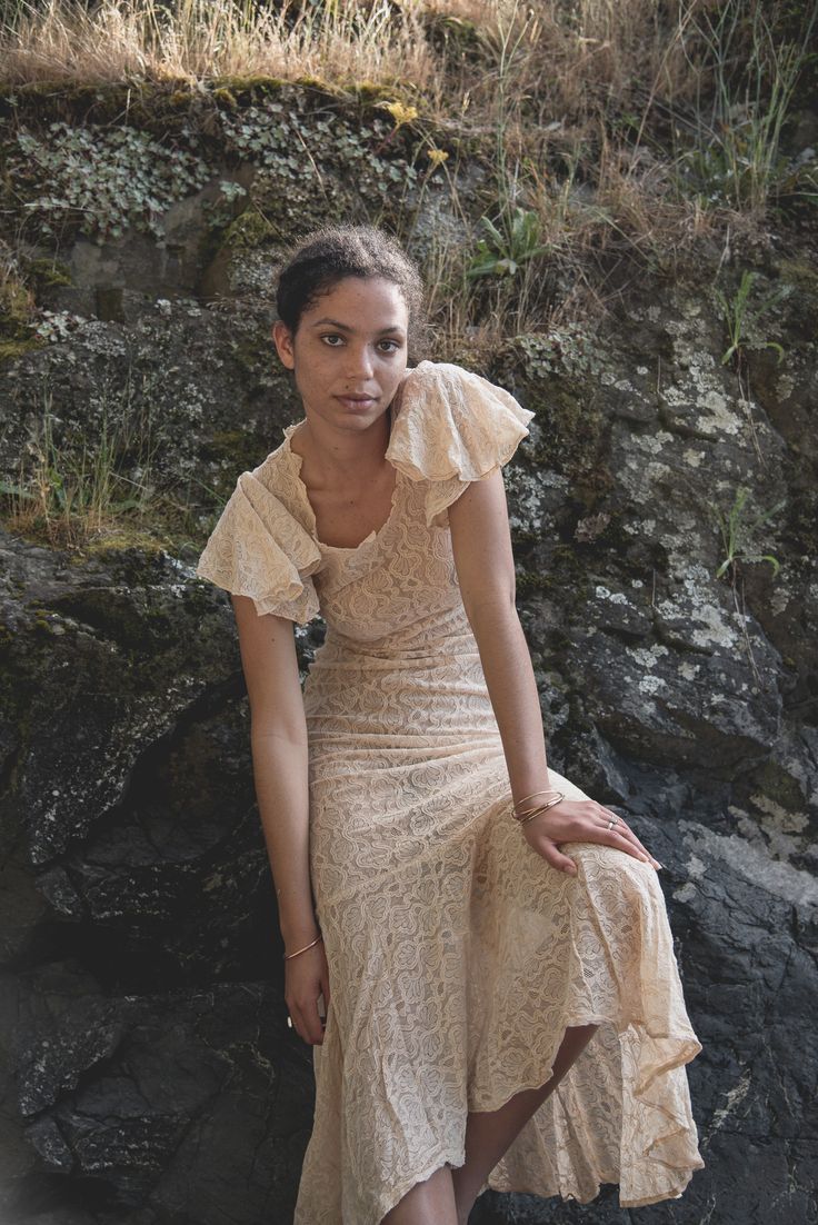 a woman in a dress sitting on a rock