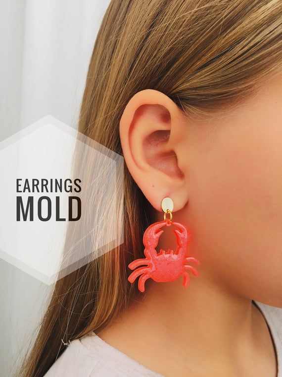 a woman wearing red earrings with a crab on it's back drop earring