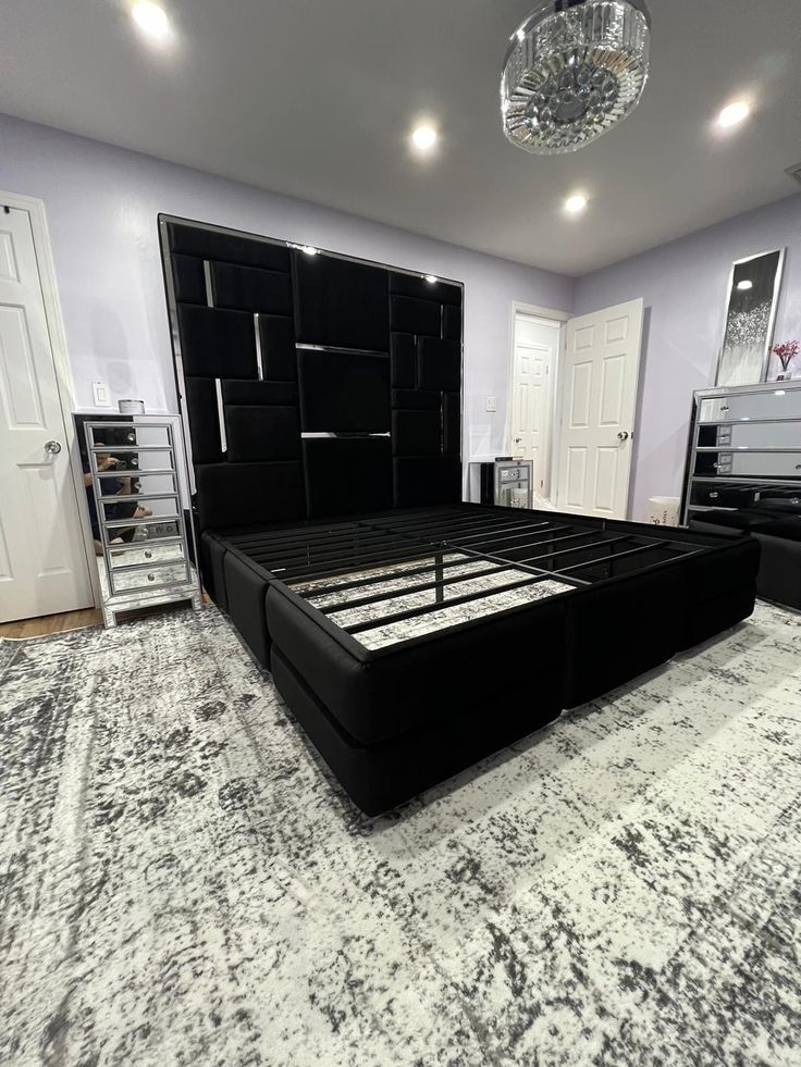 a large black bed sitting on top of a carpeted floor