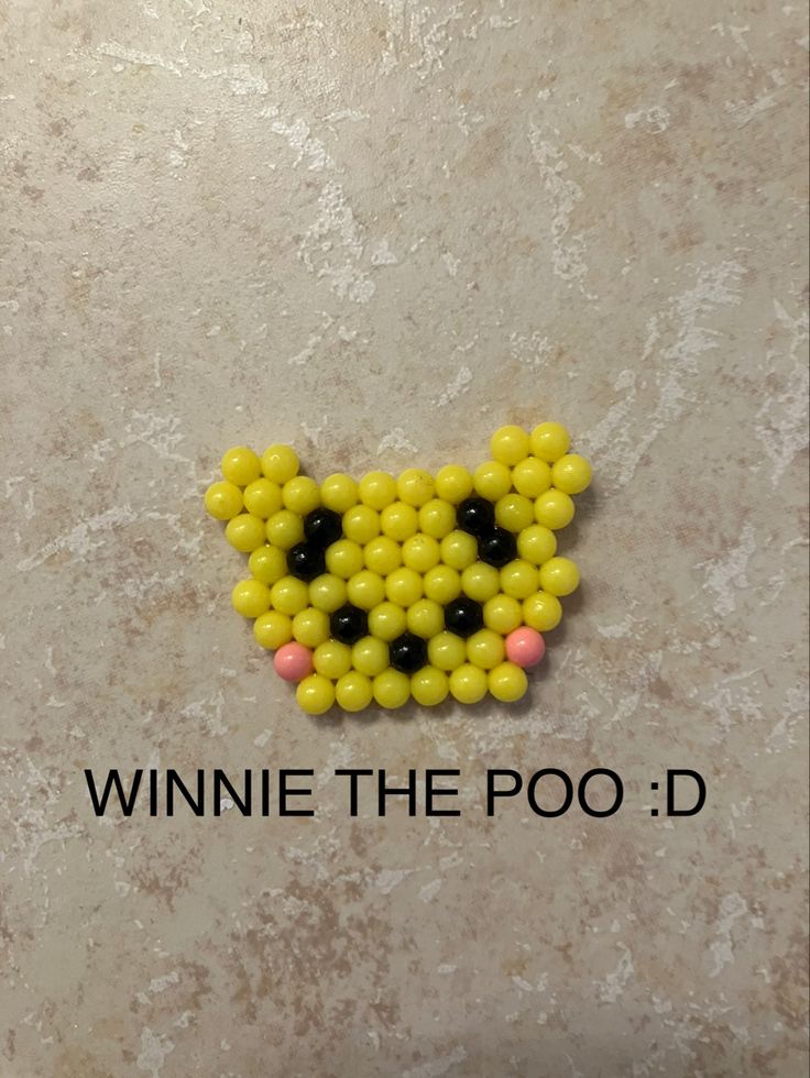 a yellow and black beaded cat on top of a marble surface with the words winnie the poo d above it