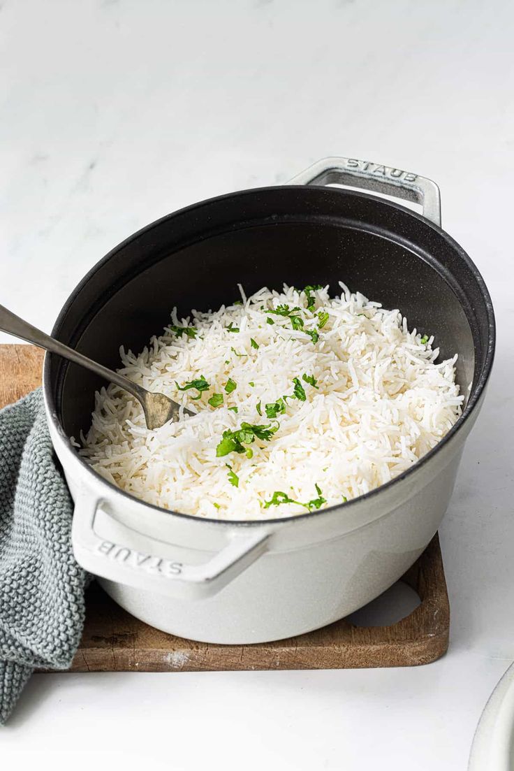 a pan filled with white rice on top of a cutting board next to a knife