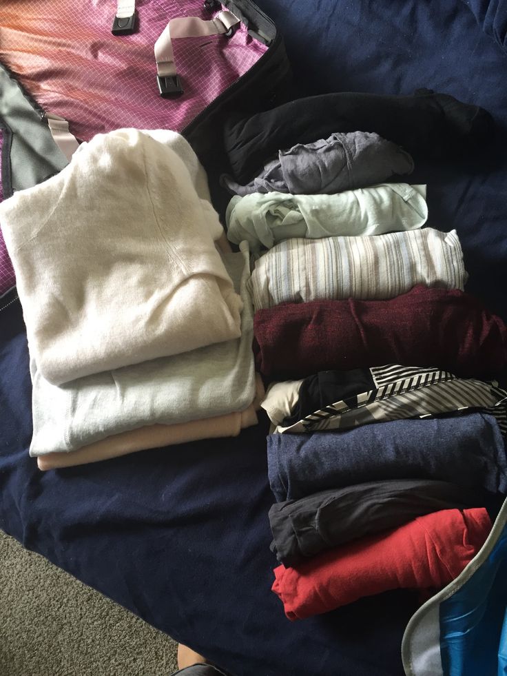 a pile of clothes sitting on top of a bed