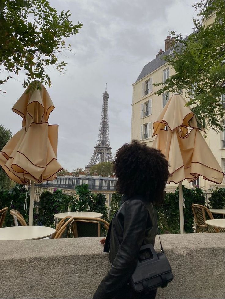 a woman walking past some umbrellas in front of the eiffel tower