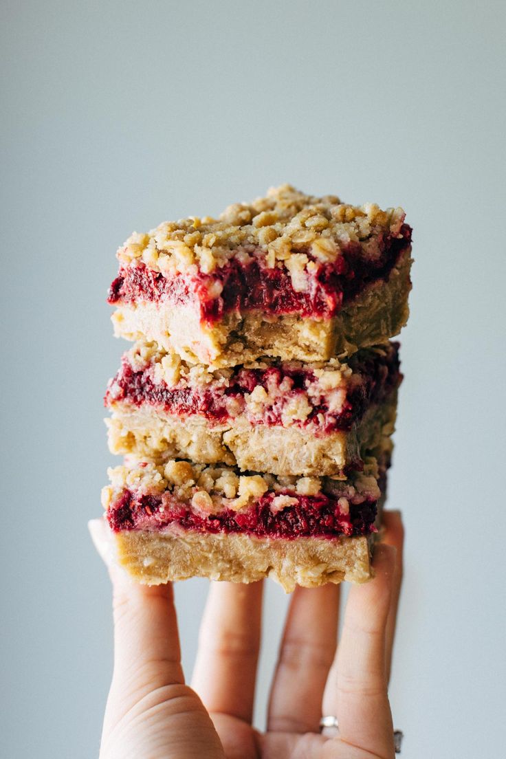 two pieces of food are stacked on top of each other in front of a person's hand