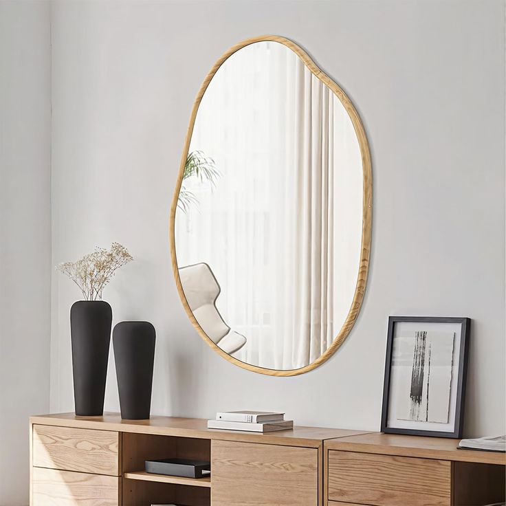 a large round mirror hanging on the wall above a wooden dresser in a living room