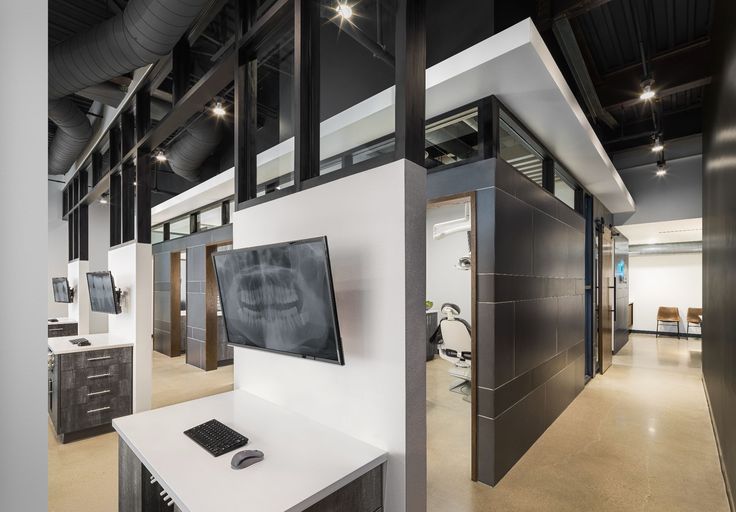 an office with a large flat screen tv mounted on the wall next to a white desk