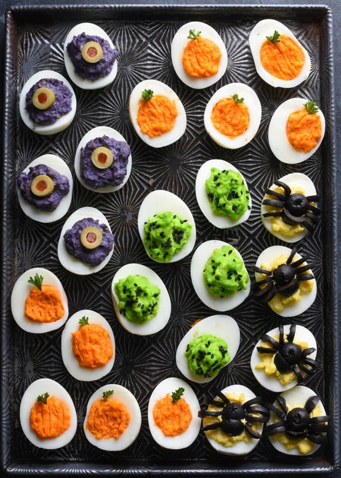 deviled eggs decorated with halloween decorations on a tray