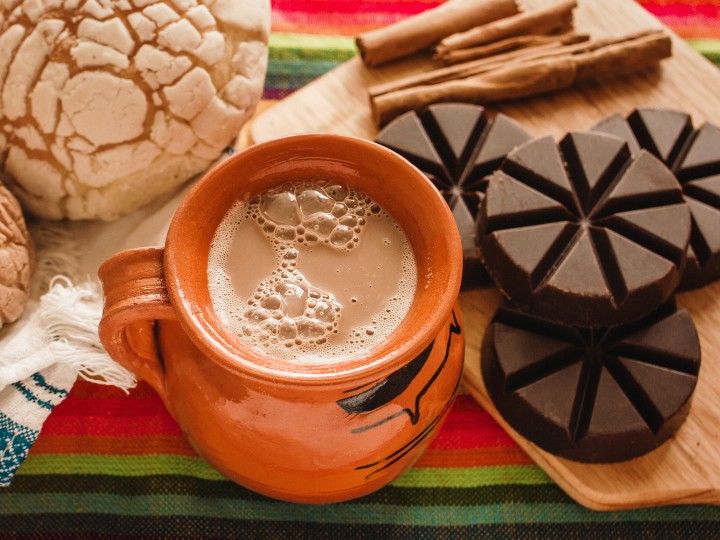 a cup of hot chocolate next to some cookies and other food items on a table