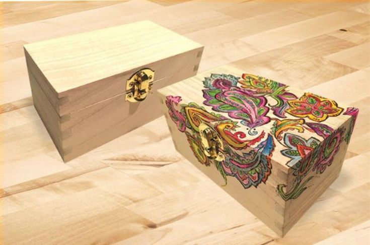 two wooden boxes with designs on them sitting on a wood floor next to each other