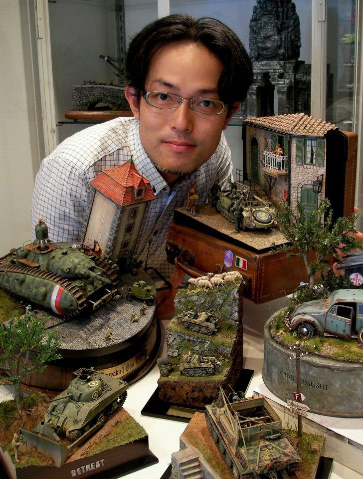 a man standing in front of several model army vehicles and tanks on display at a table