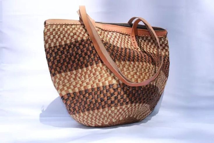 Tote bag, Woven Bag with Leather Handles, Beach Bag, Picnic Bag, Natural Bag, laptop bag, Office bag, Traveling bag This beautiful handmade Tote bag originated from craftsmen living in Eastern Community in Kenya, the Akamba. Our Tote bags are woven using colored sisal and leather hands.The woven bag is made from products which are entirely eco-friendly and sustainable, leather to provide comfort and padding. Leathers are naturally tanned from cows and camel. It has a zipper. This Tote bag is really stylish, functional and eco-friendly for everyday use, summer travels and beyond. From travel to work or a night out, makes it easier to fill your closet with ethical, high quality staples for every occasion. It's dimensions are approximately; 12" Widh  x 12" Height (excluding the handle). T.hey Brown Woven Shoulder Beach Bag, Casual Brown Handwoven Beach Bag, Casual Brown Handwoven Bag, Brown Woven Satchel Beach Bag, Casual Natural Color Bags With Weaving, Casual Brown Weaving Bags, Brown Beach Bag With Weaving For Travel, Brown Weaving Beach Bag For Daily Use, Brown Woven Basket Beach Bag