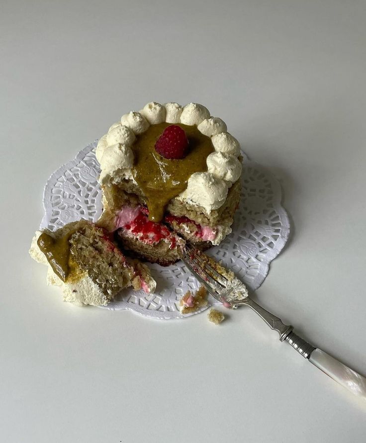 a piece of cake on a white doily with a fork next to it and another slice missing