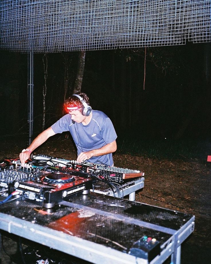 a man in headphones is playing music on a dj's deck at night