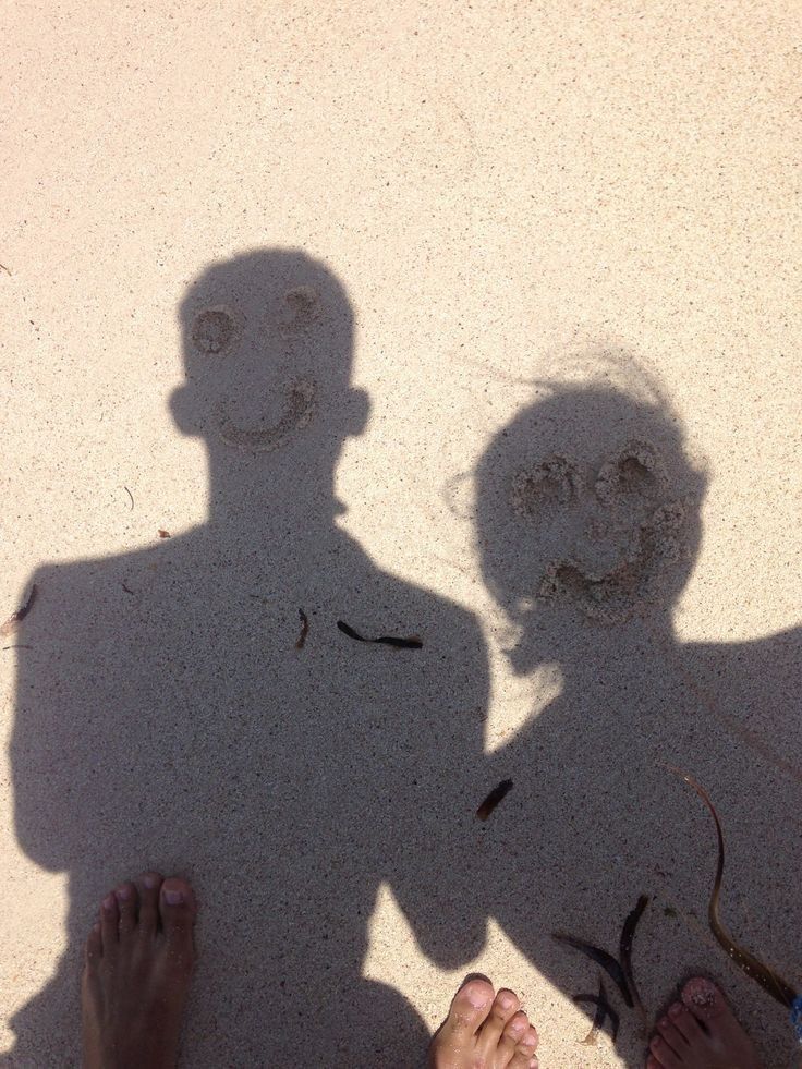 two people standing next to each other with their shadows on the ground and one person's shadow