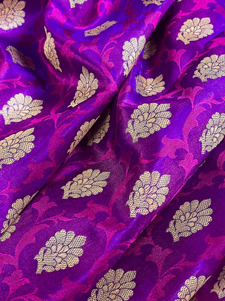 Gorgeous Banarasi Tanchoi Silk Saree. Handpicked from weavers of Banaras. Its a beautiful Half and half saree with Tanchoi and Buttis work on the half of the saree and the other half is just the tanchoi work. Item : Saree Color : Purple with Red with Muted Gold Zari Weave  Base Fabric : Banarasi Tanchoi Silk Blouse piece : Yes Blouse material : Banarasi Silk Work : Handwoven, handloom, zari woven, Handmade Fall & Edging(Pico) Yes/No : Yes Disclaimer -: - Color variation is possible due to variou Navratri Purple Brocade Traditional Wear, Purple Brocade Traditional Wear For Navratri, Diwali Brocade Handloom Saree, Diwali Handloom Brocade Saree, Art Silk Fabric For Puja During Diwali, Festival Brocade Saree With Zari Weaving, Traditional Handloom Brocade Saree, Anarkali Brocade Blouse With Motifs, Brocade Blouse Piece With Self Design For Diwali