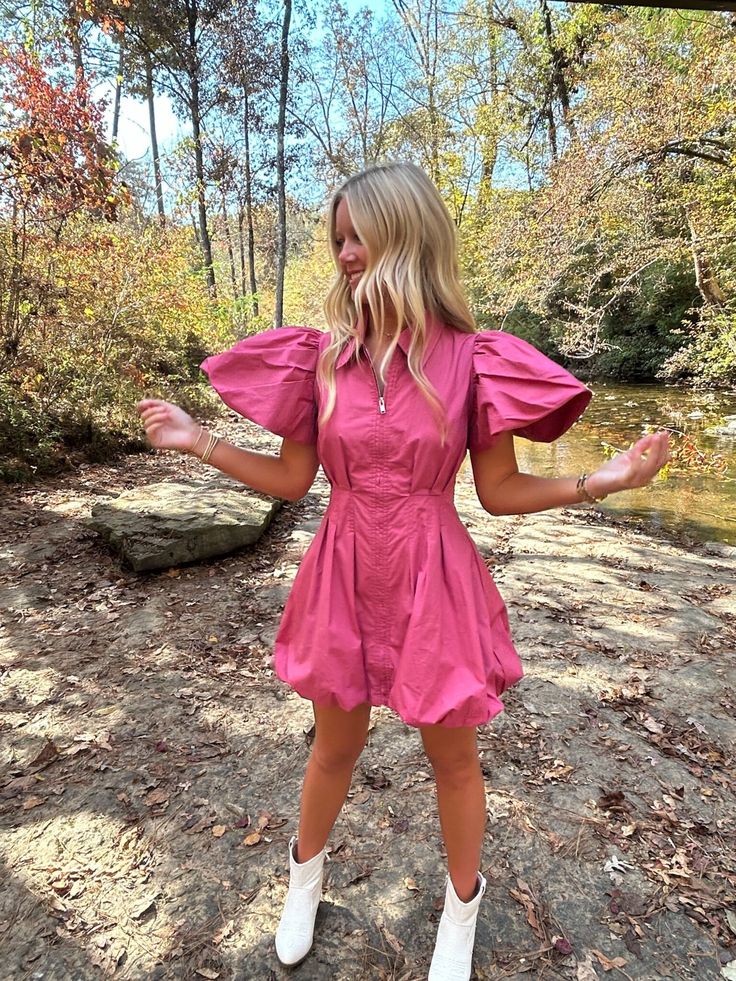 a woman in a pink dress is standing on the ground with her arms out and hands outstretched